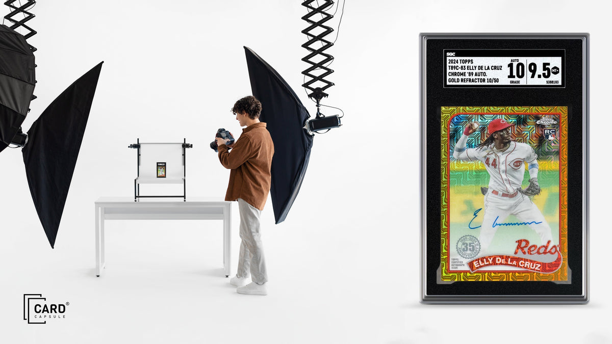 Photographer using a lightbox and softbox lighting to shoot cards, beside an enlarged graded slab
